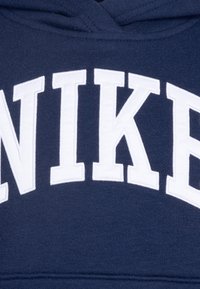 Sudadera con capucha azul marino que presenta un destacado logotipo bordado en blanco de "NIKE" en la parte frontal. Textura suave y diseño tradicional.