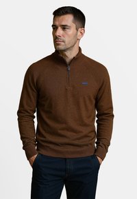 Pull en tricot marron avec un col haut et une fermeture �éclair d'un quart. Présente des poignets et un ourlet côtelés. Design simple, sans motifs ni logos visibles.