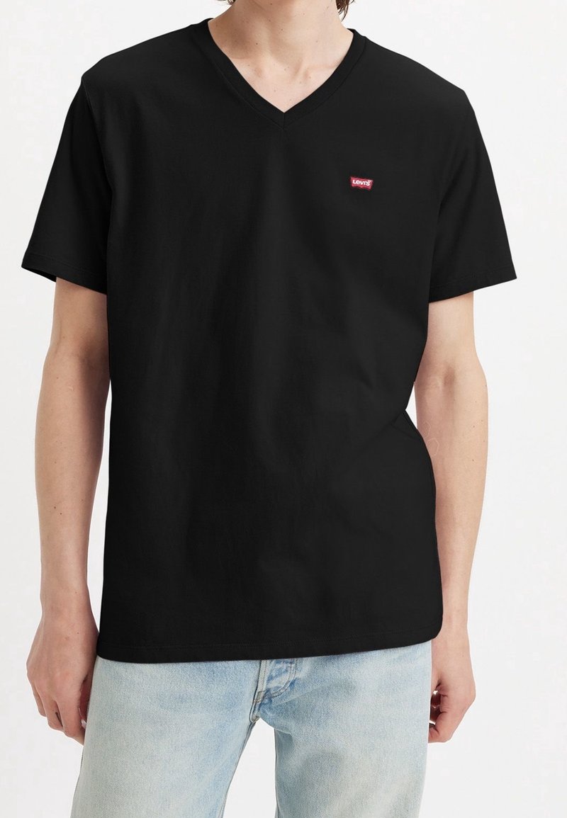 Camiseta de algodón negra con cuello en V y mangas cortas, con un pequeño logo rojo de Levi's en el lado izquierdo del pecho y un corte relajado.