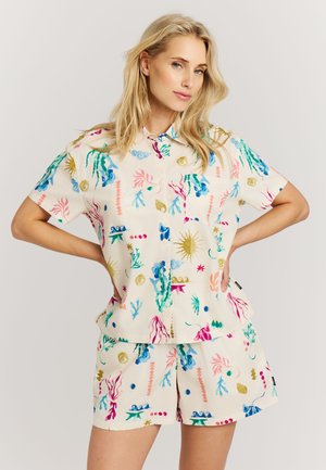 Ensemble composé d'une chemise à manches courtes à boutons et d'un short couleur crème clair, avec des imprimés abstraits colorés sur le thème sous-marin en rose, bleu et vert.