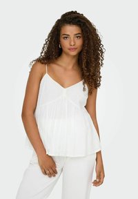 Witte mouwloze top met een V-hals, voorzien van delicate geborduurde patronen en een vloeiende, losse pasvorm. Gepaard met witte broek.