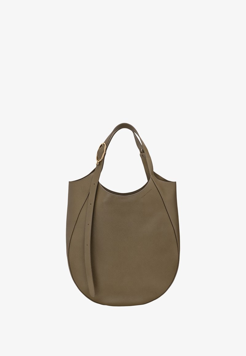 Brown leather tote bag with rounded bottom, adjustable strap, and gold-tone buckle detail, set against a white background.