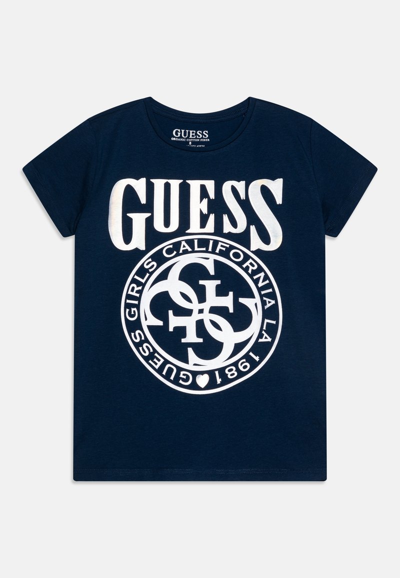 Camiseta de algodón orgánico azul marino con gran texto blanco "GUESS" y un gráfico circular con "CALIFORNIA" y otros elementos textuales.