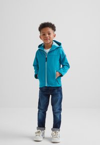 Turquoise hooded jacket with zippered front, two side pockets, and light blue lining, paired with dark jeans and white sneakers.