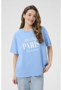 Světle modré tričko s krátkým rukávem, na kterém je bílej text "TRÈS CHIC PARIS Toujours à la mode." Vyrobeno z bavlny s volným střihem.