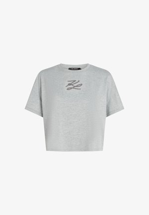 Siva kratka majica iz mehkega blaga. Ima okroglo izreznico in kratke rokave s subtilnim vezenim logotipom na prsih.