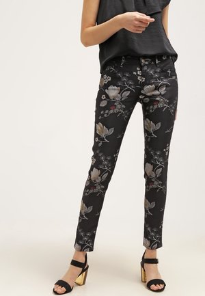 Jean noir floral avec broderie, mettant en avant de grandes fleurs dorées et des motifs complexes. Design ajusté avec une légère élasticité.