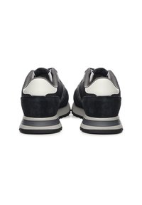 Čierne tenisky zo semišu a sieťoviny so sivým pätovým dielom, polstrovaným golierom a pruhovanou gumovou podrážkou. Na vrchnej časti majú biele akcenty.