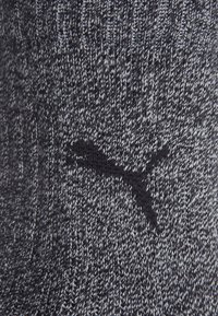 Wełniane skarpetki w ciemnoszarym kolorze z teksturowanym wzorem i czarnym haftowanym logo, oferujące dopasowane oraz miękkie wrażenie.