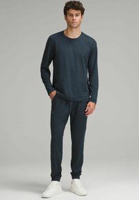 Tmavomodrá dlhá košeľa s okrúhlym výstrihom a zladenými šnúrkovými nohavicami. Mäkký materiál s rebrovanými manžetami. Nosené s bielymi teniskami.