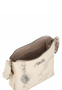 Beige Crossbody-Tasche aus Kunstleder mit Reißverschluss, mit einem gemusterten Design und einem silbernen Charm, der am Reißverschluss befestigt ist.
