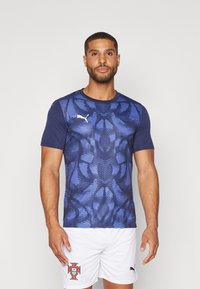 Blå mønstret kortermet idrettshemse med glatt tekstur, med Puma-logo på brystet og kontrastfargede ermer.