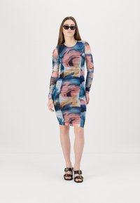 Bodycon-klänning med långa ärmar, prydd med ett flerfärgat abstrakt mönster i blå, rosa och beige nyanser. Svarta sandaler med remmar fulländar looken.