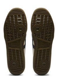 Boty Onitsuka Tiger s gumovými podrážkami, se strukturovaným vlnitým vzorem a cirkulárními akcenty. Barvy zahrnují hnědou a béžovou.