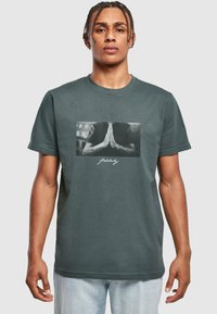 Gray cotton t-shirt featuring a front graphic of hands in a prayer position with tattoos, and the word "pray" in white script below.
