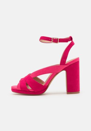 Sandalias de tacón de ante rosa con un ancho tacón de bloque, correa en el tobillo y diseño de correas cruzadas en la parte delantera. Forro interior suave.