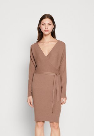 Robe portefeuille en tricot marron doux. Elle présente des manches longues, un décolleté en V profond et une ceinture en tissu à la taille. La texture côtelée ajoute un détail.