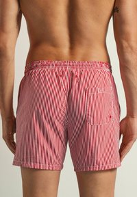 Rood-witte gestreepte zwemboxers met een elastische tailleband, zijzak en een achterzak, gemaakt van lichtgewicht stof.