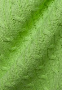 Helle grüne gestrickte Stoff, der ein strukturiertes Zopfmuster zeigt. Das Material wirkt weich und dick, mit einer glatten, gleichmäßigen Oberfläche.