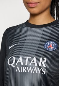 Black and gray vertically striped sports jersey with round neckline, featuring "QATAR AIRWAYS" in white, Nike logo, and Paris Saint-Germain crest.