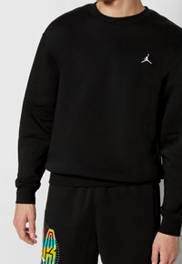 Schwarzer Pullover aus Baumwolle mit Rundhalsausschnitt und langen Ärmeln. Enthält ein weißes Jordan-Logo auf der Brust.