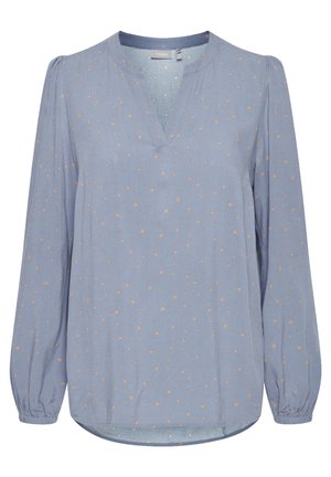 Világoskék, hosszú ujjú blúz V-nyakkal, amelyen világosabb árnyalatú pöttyös minta található. Puha anyag, meghúzott mandzsettákkal és laza szabással.