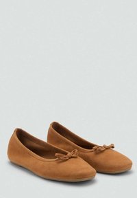 Ballerines en daim beige avec un bout rond et un détail de nœud à l'avant, dotées d'une texture douce et d'une semelle plate flexible.