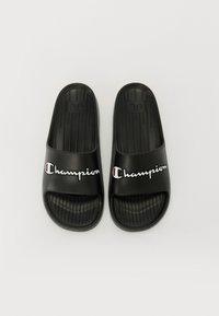 Infradito in gomma nera con soletta testurizzata, fascia larga con logo "Champion" in bianco e rosso, e scanalature sollevate per una migliore presa.