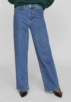 Høyt liv, vide blå jeans laget av denim. Har knappeåpning, fem lommer og sømmer. Rent, uforfalsket design.