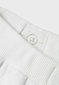 Witte kledingband met een zichtbare ribbeltextuur en een ronde doorzichtige knop met een ontwerp met vier gaten.