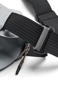 Borsa in tessuto grigio con cinghie in tessuto nero, dotata di fibbia metallica, cursore della cerniera e dettagli strutturati per durata e funzionalità.