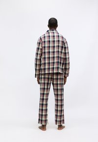 Karierte Pyjamas in Marineblau, cremefarben und rot. Locker sitzendes Hemd mit Kragen und passende Hose. Weiches Baumwollmaterial, gerade Schnittform.