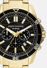 Kuldse tooni meeste kronograaf kell musta tekstureeritud dials, kolme alam-tee, kuupäeva kuvamine ja helendavad tunni markerid. Veekindel kuni 100 meetrit.