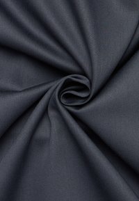 Tessuto grigio scuro con una superficie liscia e leggermente texturizzata, disposto a spirale, che indica flessibilità e caduta.