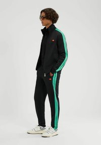 Zwart trainingspak met teal zijkraag; zip-up jack met kraag, elastische mouwen, logo; bijpassende broek met zakken en gebreide enkels.