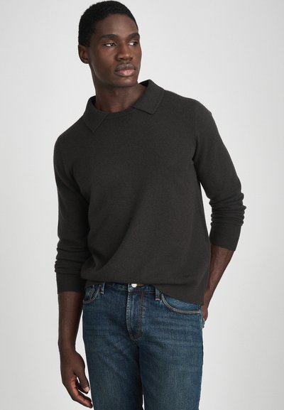 Pull en maille gris foncé avec un col plat, des manches longues et des poignets côtelés, associé à un jean en denim bleu. Texture lisse et design simple.