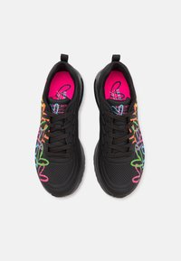 Un paio di sneaker nere con lacci, decorate con accenti in stile graffiti colorati e solette rosa brillante, viste dall'alto su uno sfondo bianco.
