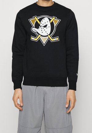 Sweatshirt noir avec un grand dessin animé de fantôme et un logo de crosses de hockey croisées en blanc, or et jaune sur le devant. Matériel en coton.