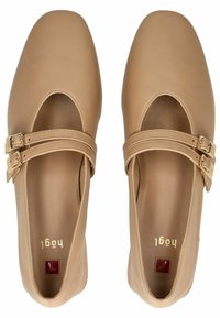 Zapatos de cuero beige con puntera cuadrada y diseño de recortes. Presentan doble hebilla en las correas y una textura suave. Logo dorado en el interior.