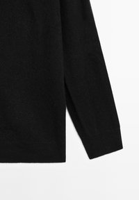 Black knitted sweater with a soft texture, featuring long sleeves, a straight cut, and side slits at the hem for added movement.