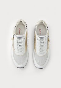 Sneakers bianchi con accenti dorati e argentati, texture in rete e una cerniera laterale. Presentano un motivo a righe sui lati.