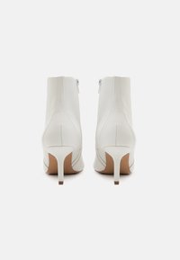 Weiße Leder-Stiefeletten mit einem eleganten Design, spitzem Zeh und dünnen Absätzen. Verfügt über einen Reißverschluss auf der Rückseite und eine glatte Textur.