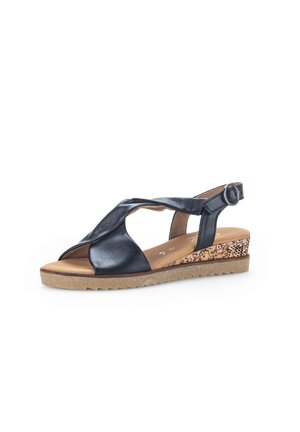 Black leather wedge sandal with open toe, crisscross straps, adjustable ankle buckle, and textured light brown sole with patterned wedge heel.