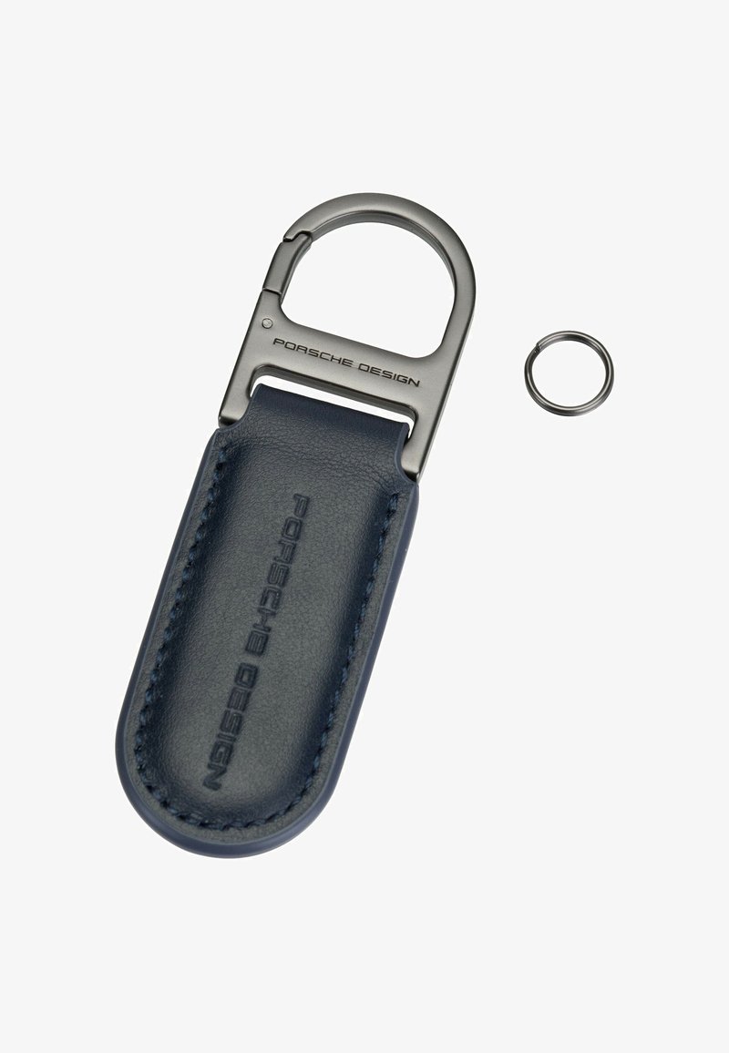 Porte-clés avec bracelet en cuir bleu marine embossé "Porsche Design" et fermoir en métal gravé "Porsche Design", accompagné d’un petit anneau en métal.