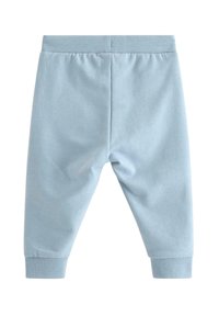 Vaaleansiniset puuvillaiset collegehousut, joissa on resorivyötärö ja -hihansuut, sileä pinta ja kapeneva lahjemalli.