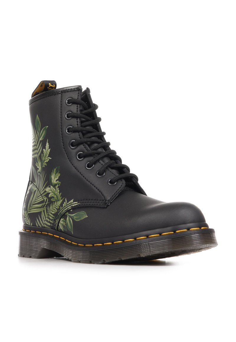 Schwarzer Schnürstiefel mit gelber Naht und grünen blattförmigen Farnmustern an der Seite, mit einer dicken strukturierten Sohle.