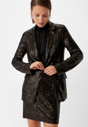 Black sequined blazer with a matching skirt, featuring a fitted design and a shiny, textured surface. The blazer is buttoned and has lapel details.