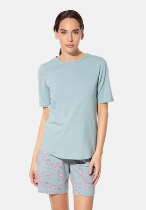 Helle blaue Baumwoll-T-Shirt mit kurzen Ärmeln und rundem Ausschnitt, kombiniert mit kurzärmligen Shorts im floralen Muster in ähnlichen Farbtönen.