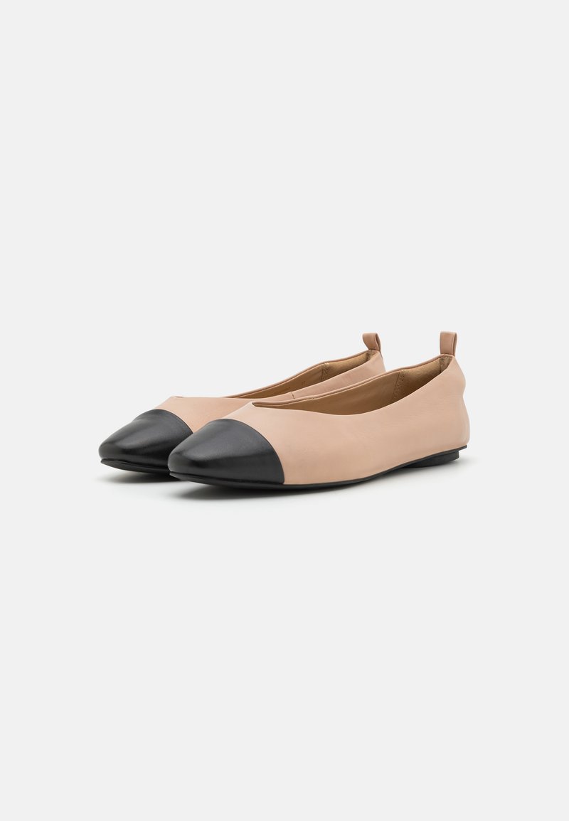Płaskie buty z gładką, jasnobeżową cholewką i czubkiem w kształcie szpica w kolorze czarnym. Posiadają miękką teksturę oraz małą pętelkę z tyłu, ułatwiającą zakładanie.