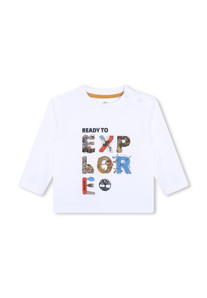 Camisa blanca de manga larga con un gráfico multicolor "LISTO PARA EXPLORAR", que incorpora diversas texturas y objetos ilustrados.